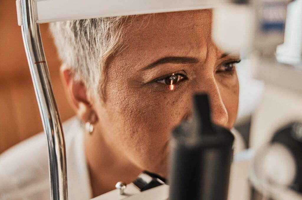 Laser, vision or senior customer in eye exam for eyesight at optometrist office in assessment or consultation. Face of mature woman testing or checking vision to help iris or retina visual health
